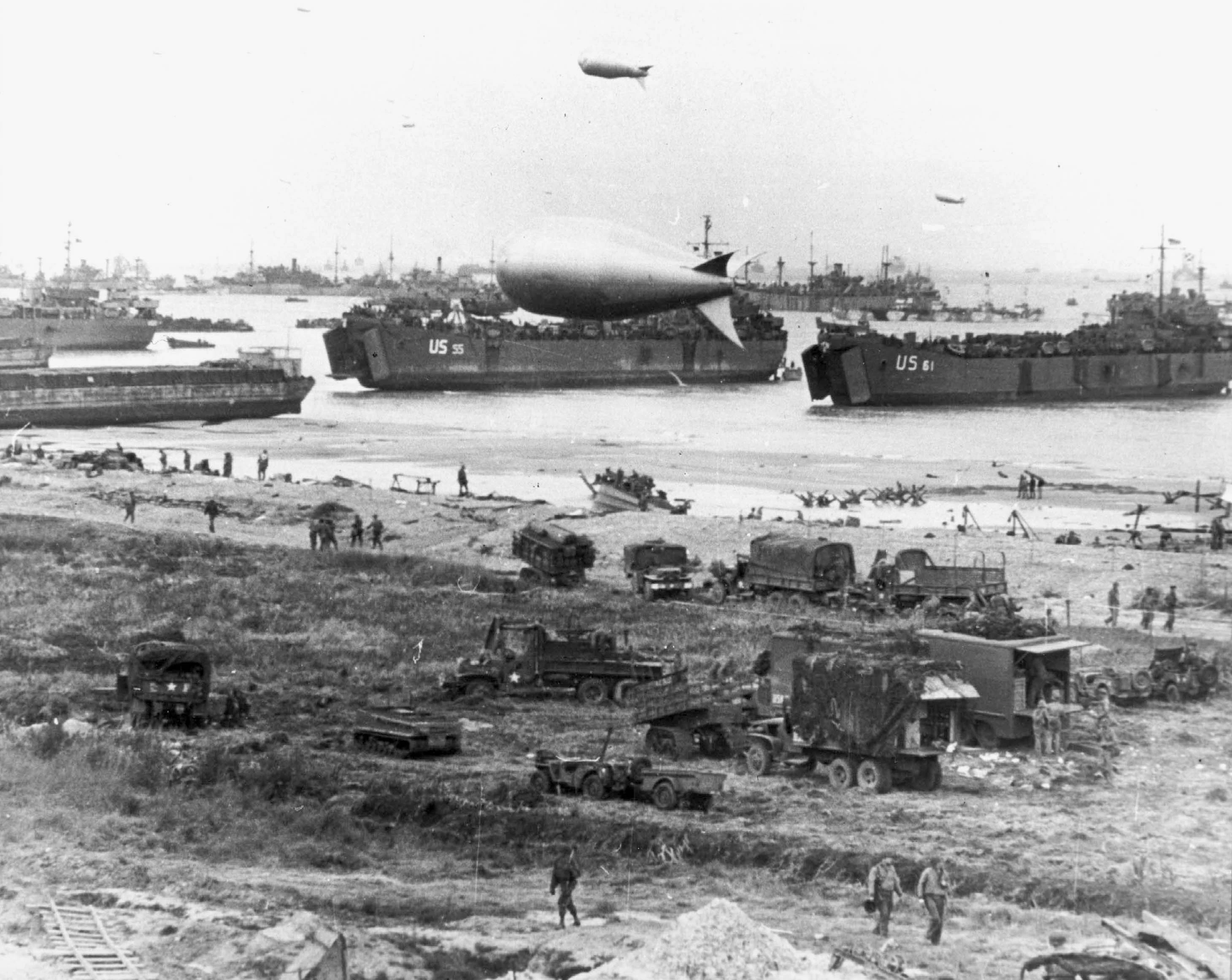 U.S. Navy LSTs and other vessels unloading at low tide at Normandy, soon after the June 1944 invasion. USS LST-55 is in the center, behind the closest barrage balloon. USS LST-61 is at right.?w=200&h=150