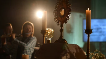 A monstrance with the Blessed Sacrament is displayed on the altar during Eucharistic adoration at a Loretto Community Pentecost event accompanied by live music.