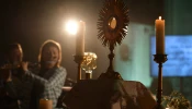 A monstrance with the Blessed Sacrament is displayed on the altar during Eucharistic adoration at a Loretto Community Pentecost event accompanied by live music.