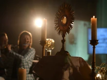 A monstrance with the Blessed Sacrament is displayed on the altar during Eucharistic adoration at a Loretto Community Pentecost event accompanied by live music.