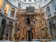 A Greek Orthodox monk pours oil into the lamps in front of the edicule of the Holy Sepulcher, which contains the venerated tomb. The three communities responsible for the Holy Sepulcher are the Greek Orthodox, the Latin Catholic, and the Armenian. Every movement and schedule inside the basilica is governed by the Status Quo.