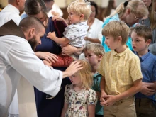 Father Michael Herlihey, OFM Cap, one of three chaplains serving pilgrims along the Drexel Route, blesses children following the opening Mass of the 2025 Eucharistic Pilgrimage in Indianpolis on May 18, 2025.