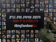 A soldier passes by a wall covered with photos of hostages held by Hamas after the deadly Oct. 7, 2023, attack in a Tel Aviv train station on Jan. 14, 2025, Tel Aviv, Israel.