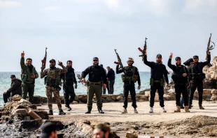 Members of security forces loyal to the interim Syrian government hold up their firearms as they stand by the Mediterranean sea coast in Syria’s western city of Latakia on March 9, 2025. Syria’s interim president, Ahmed al-Sharaa, called for national unity and peace on March 9 amid growing international backlash following the killing of civilians along the country’s coast in the worst violence since the overthrow of former president Bashar al-Assad in the heartland of the Alawite minority, to which the latter belongs. Credit: OMAR HAJ KADOUR/AFP via Getty Images