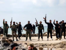 Members of security forces loyal to the interim Syrian government hold up their firearms as they stand by the Mediterranean sea coast in Syria’s western city of Latakia on March 9, 2025. Syria’s interim president, Ahmed al-Sharaa, called for national unity and peace on March 9 amid growing international backlash following the killing of civilians along the country’s coast in the worst violence since the overthrow of former president Bashar al-Assad in the heartland of the Alawite minority, to which the latter belongs.