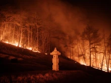 A wildfire blazes next to a stone lantern of family tomb in Andong, South Korea, on March 26, 2025. At least 18 people have been killed in one of South Korea’s worst wildfire outbreaks, with multiple blazes burning and causing “unprecedented damage,” the acting president said.