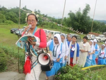 Women baptized by Prem Bhai climb to his memorial singing devotional songs during a 2018 observance of the Catholic missionary.