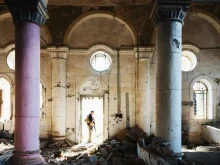 An unknown security guard stands at the entrance of a church destroyed during the fighting with ISIS in Mosul, Iraq.